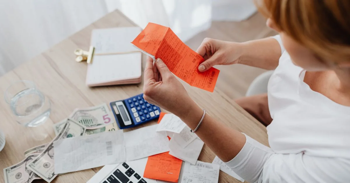 Femme utilisant une calculatrice et des reçus au bureau à domicile pour la gestion financière.