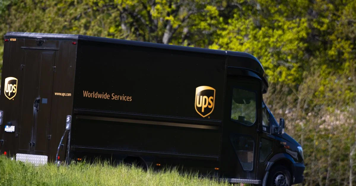 Un camion de livraison UPS circule sur une route de Jönköping, en Suède, entourée d'une végétation luxuriante.