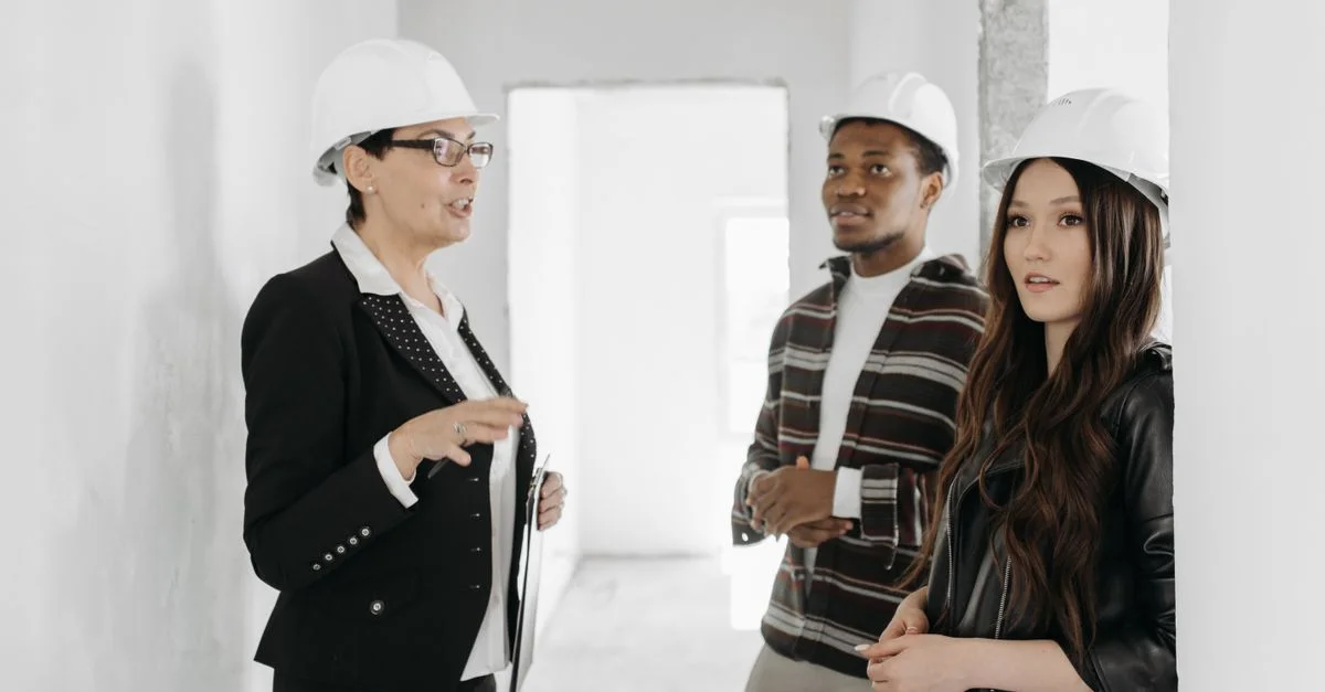 Un agent immobilier parle à des clients dans un appartement inachevé portant des casques.