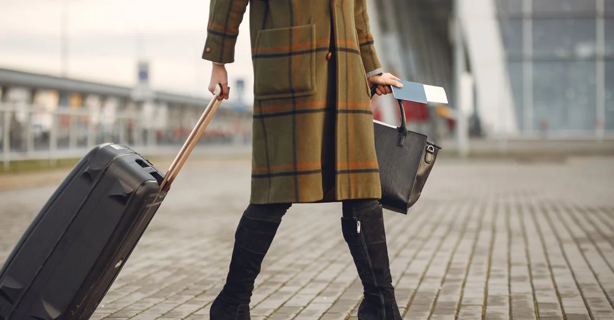 Femme élégante tire sa valise à l'aéroport, prête pour le voyage.