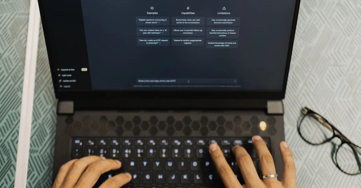 Mains tapant sur un ordinateur portable avec ChatGPT ouvert, thème de la technologie sans fil.