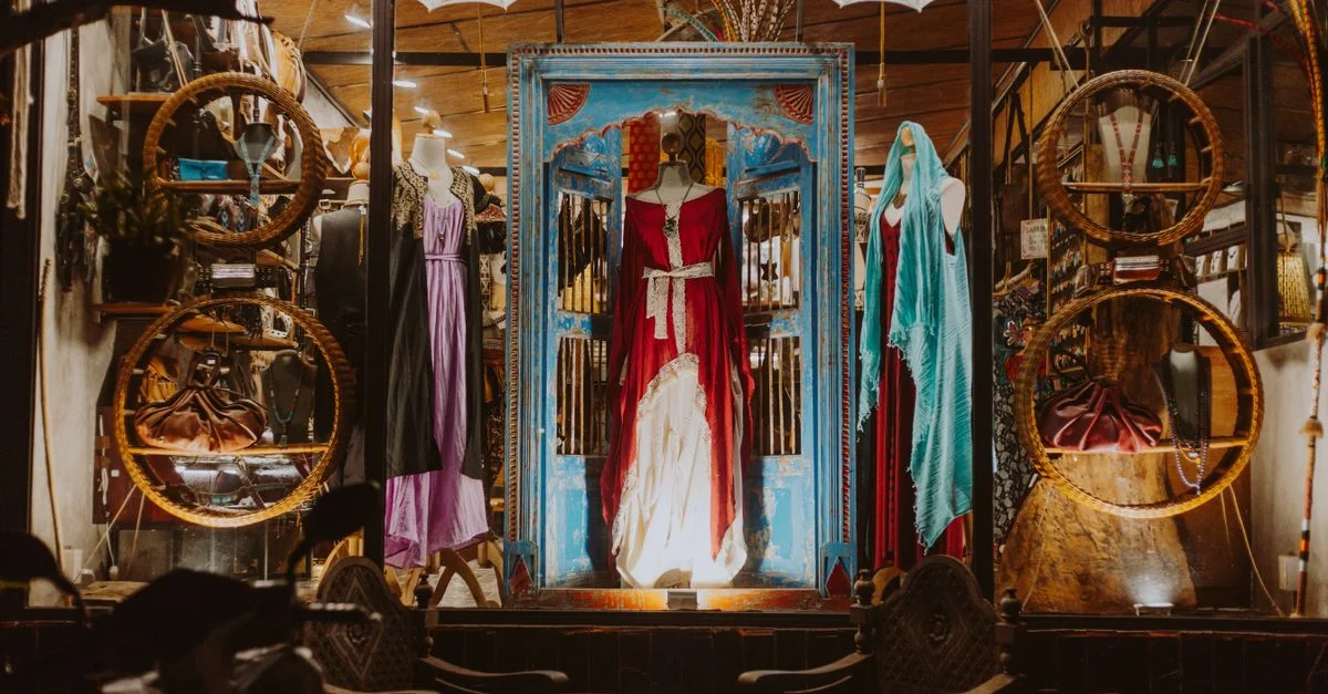 Une vitrine vibrante présentant des robes élégantes avec une décoration artistique.