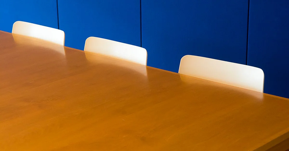 Une salle de réunion intérieure moderne et épurée avec une table en bois contre un mur bleu.