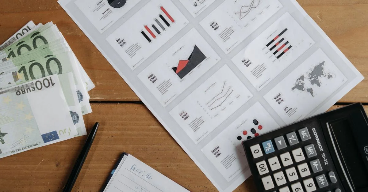 Billets en euros, graphiques et calculatrice sur une table en bois préparée pour l'analyse financière.