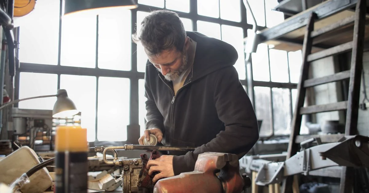 Un artisan concentré utilisant des machines dans un atelier en désordre.