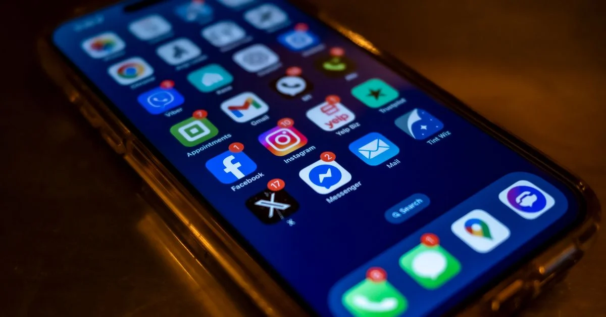 Écran de smartphone affichant des notifications d'applications de réseaux sociaux dans un environnement faiblement éclairé.