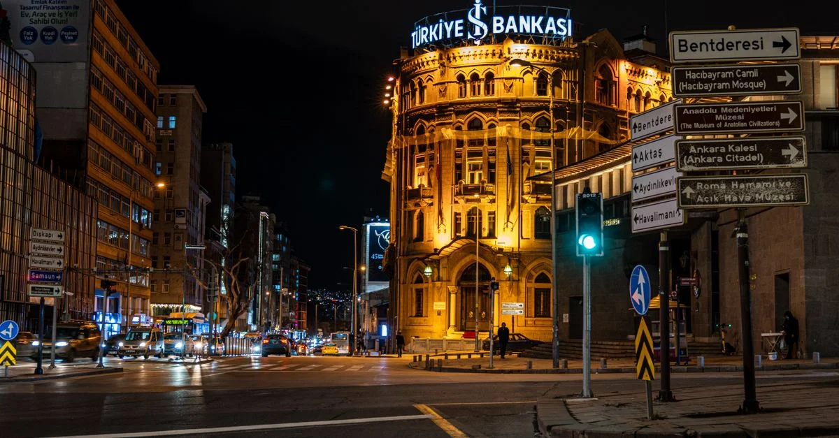 Le bâtiment illuminé de la Türkiye İş Bankası à Ankara la nuit, capturant la vie urbaine et l'architecture vibrantes.
