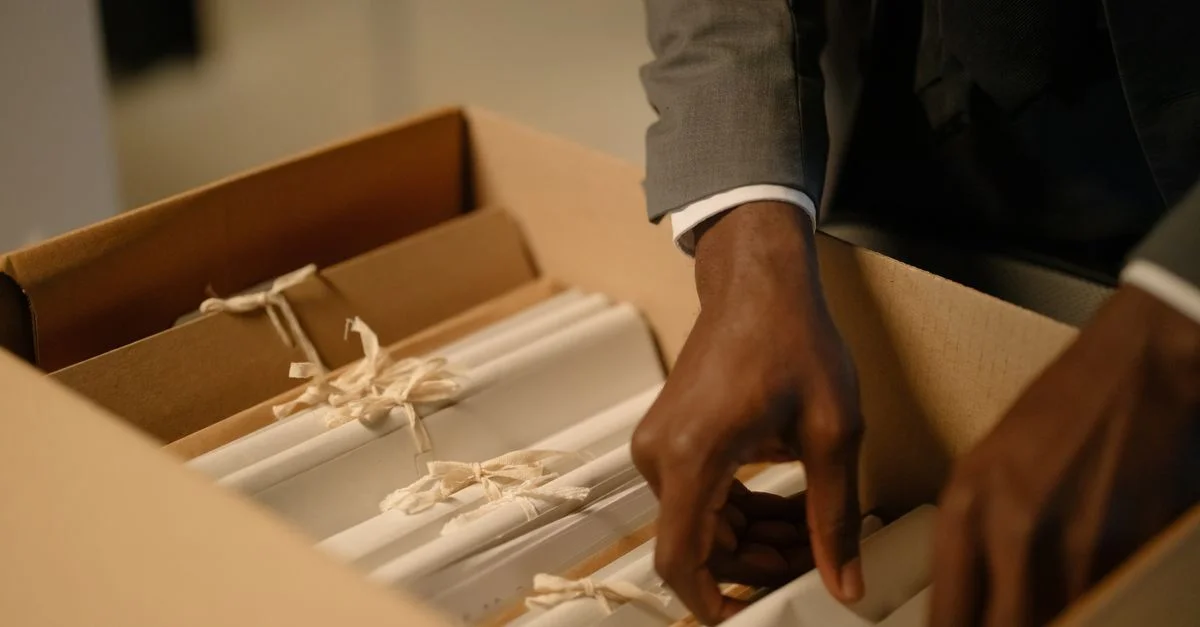 Gros plan d'un professionnel arrangeant des documents liés à l'intérieur d'une boîte, symbolisant l'organisation et l'efficacité.