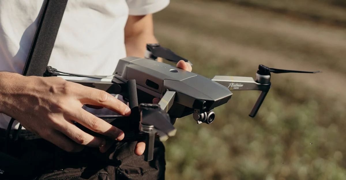 Gros plan sur un homme tenant un drone en plein air, mettant en avant la préparation de la technologie des drones.