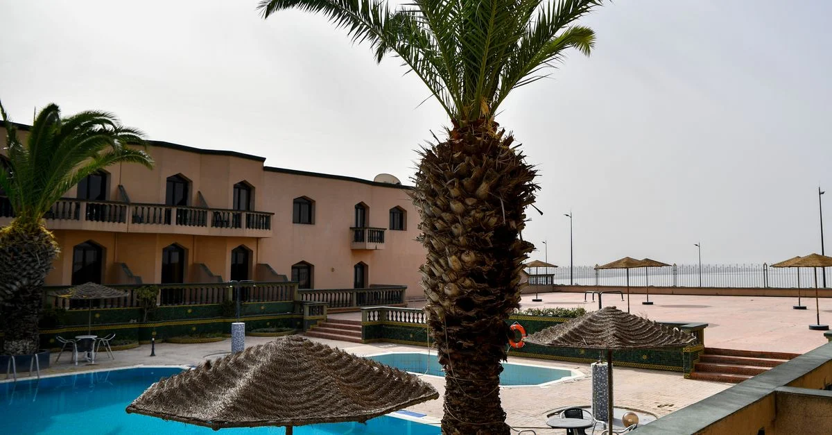 Complexe tranquille à Safi, Maroc, avec piscine, palmiers et sièges extérieurs, idéal pour des vacances relaxantes.