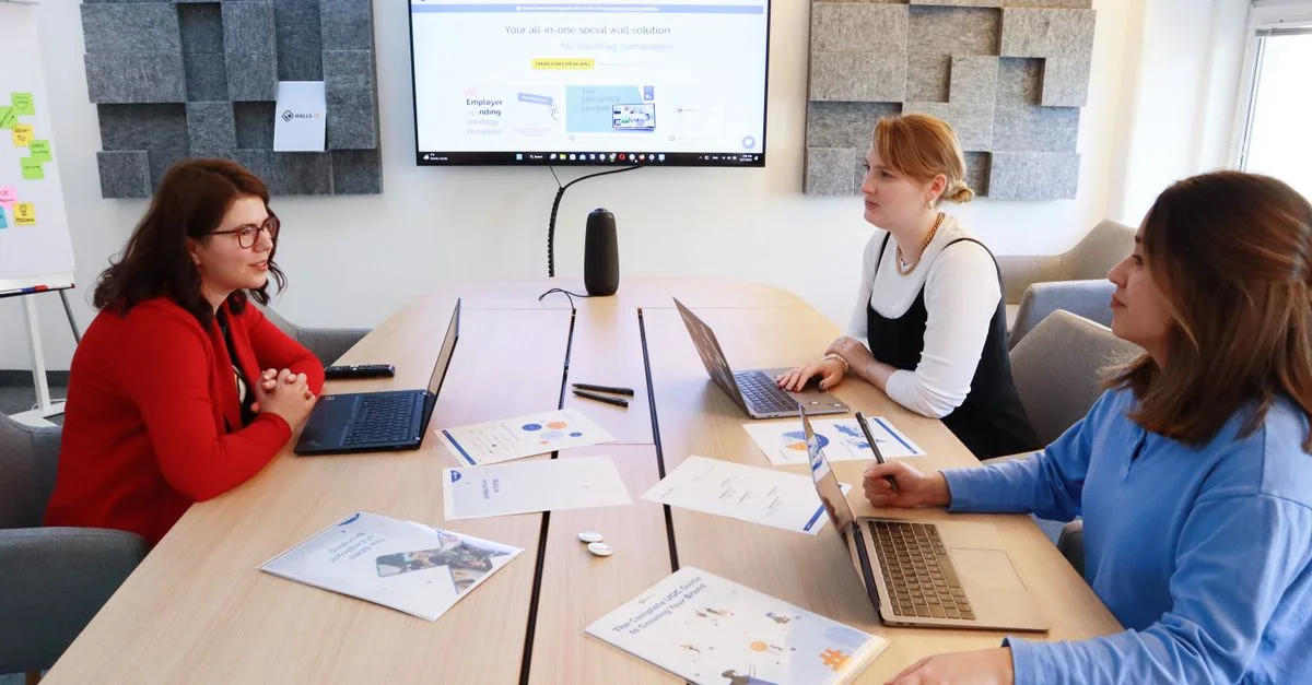 Femmes discutant de la stratégie commerciale dans un bureau moderne lors d'une réunion d'équipe.