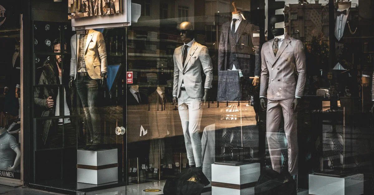 Costumes élégants pour hommes sur des mannequins dans une vitrine de boutique. Idéal pour des thèmes de mode et de vente au détail.