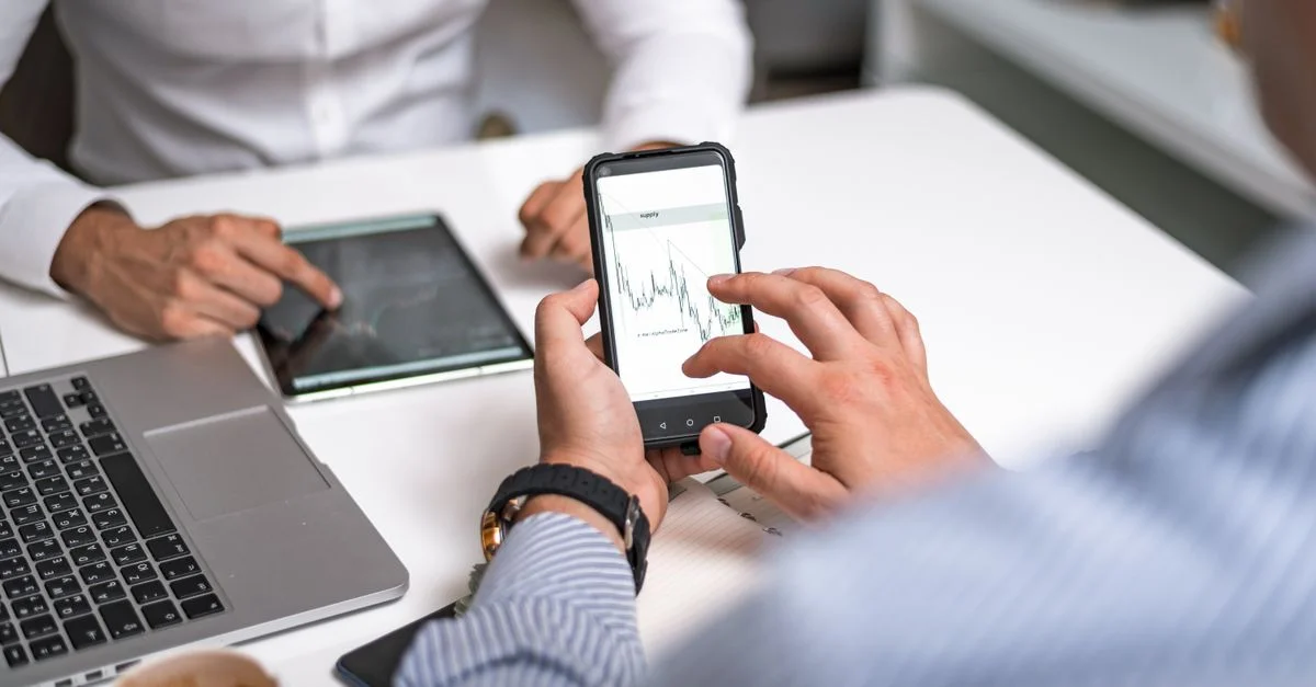 Deux professionnels analysant les tendances du marché sur des appareils numériques dans un cadre de bureau.