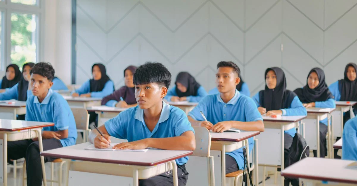 Des lycéens en uniforme étudient attentivement dans une salle de classe indonésienne.