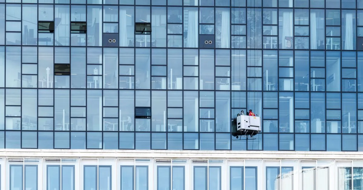Façade en verre de grande hauteur avec plateforme de nettoyage et travailleurs à Hambourg, Allemagne.