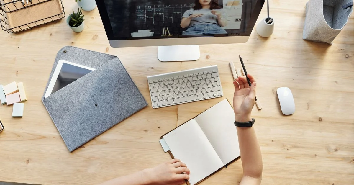 Une adolescente apprenant activement dans un espace de travail organisé à domicile via un cours en ligne sur un ordinateur de bureau.
