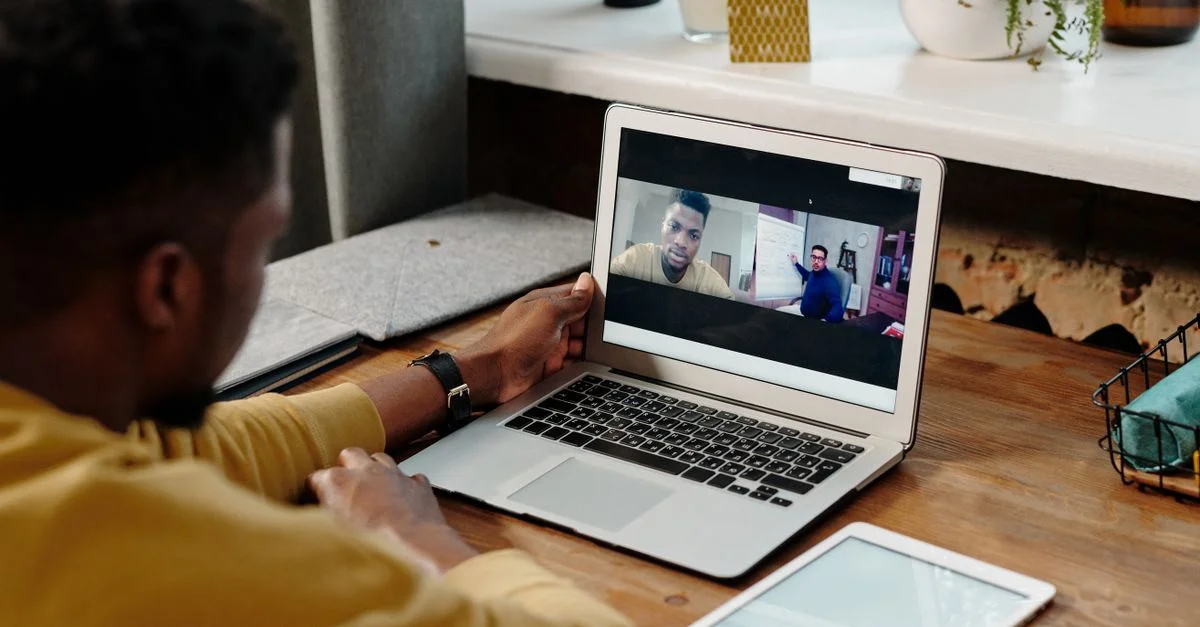 Un homme participe à une vidéoconférence en ligne depuis chez lui en utilisant son ordinateur portable, favorisant la communication à distance.
