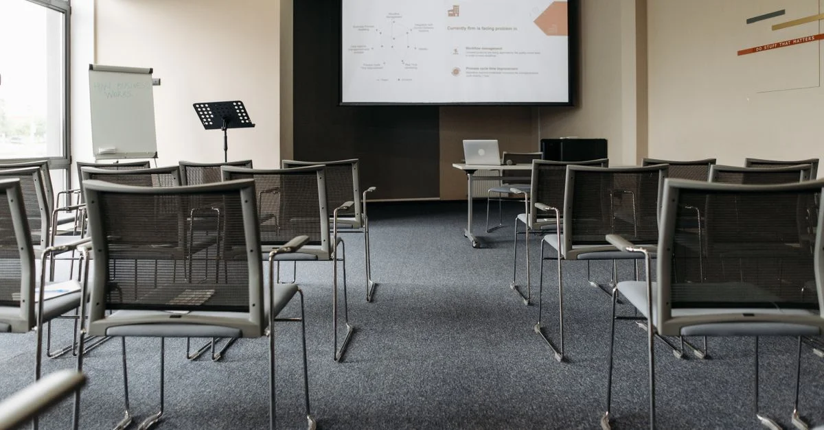 Une salle de conférence vide avec des chaises, un écran de projecteur et une configuration de présentation.