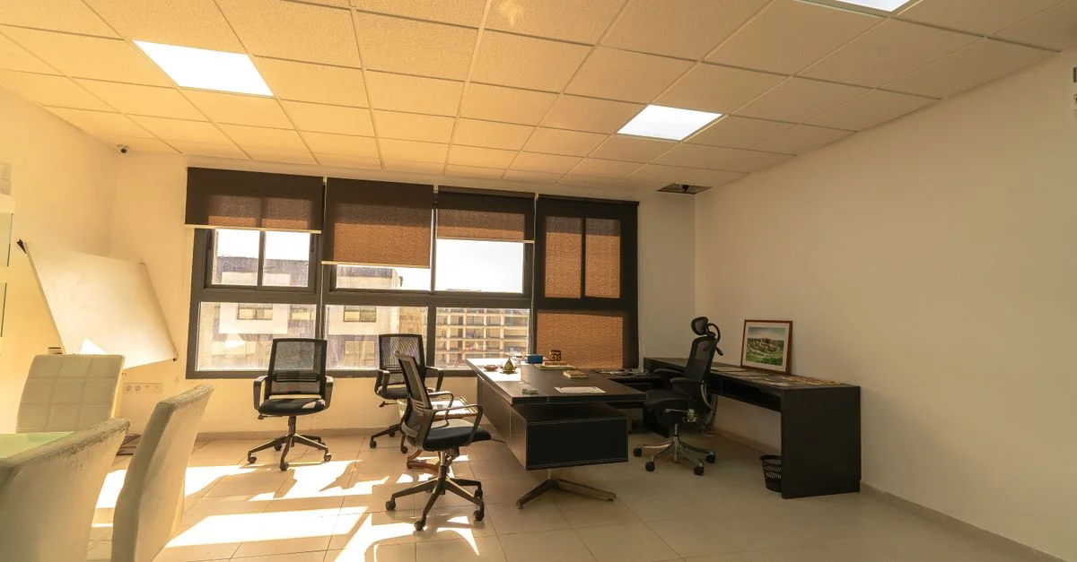 Intérieur de bureau lumineux et spacieux bénéficiant d'un éclairage naturel, comprenant des bureaux et des chaises.