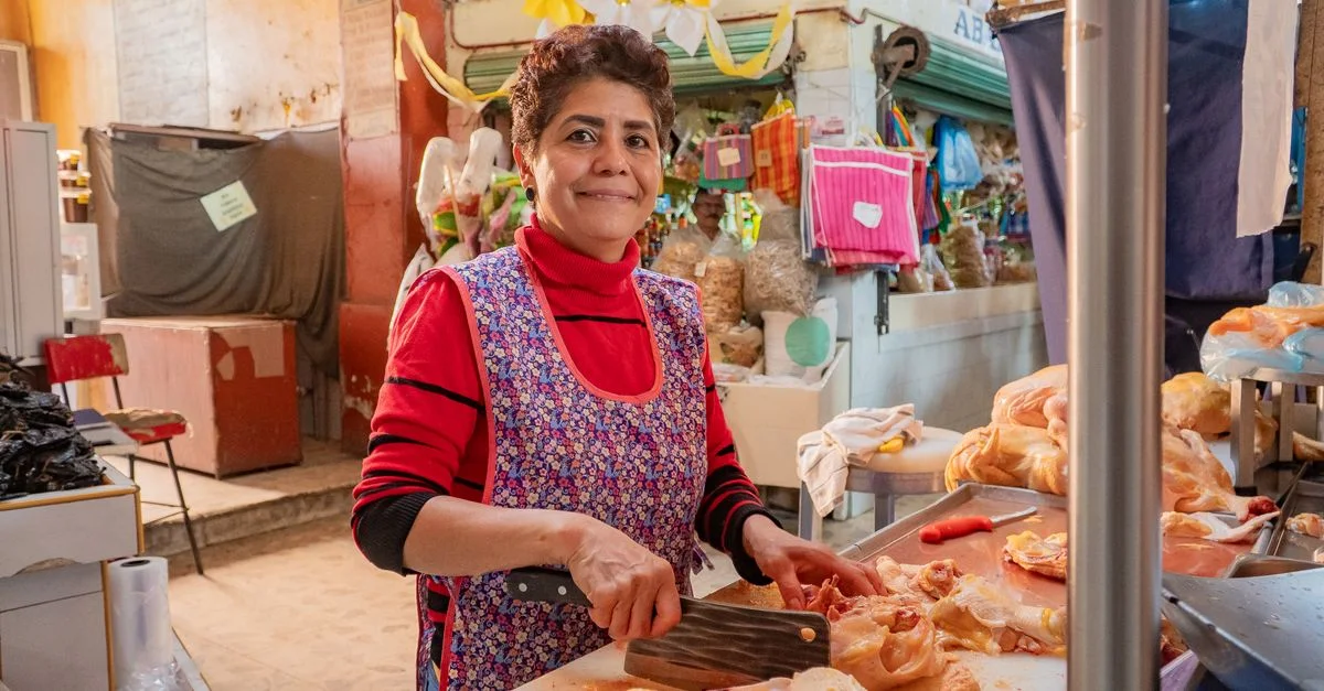 Une femme prépare du poulet sur un marché animé de Guanajuato, illustrant la vie et le commerce locaux.