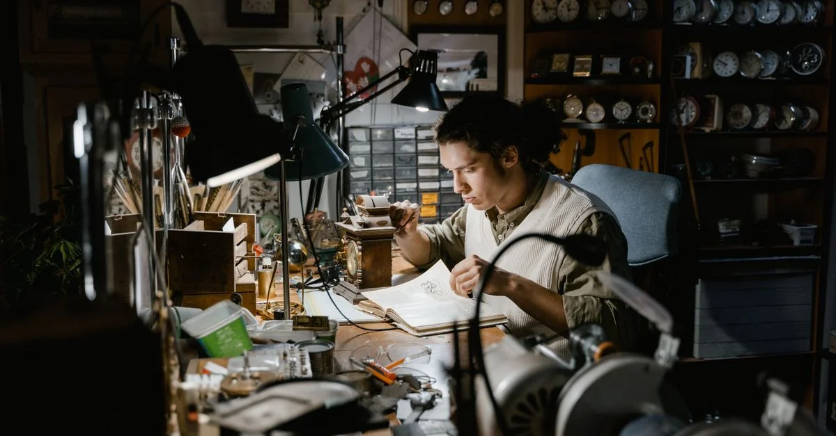 Un artisan dévoué travaille avec minutie sur une horloge dans un atelier rempli d'horloges, mettant en avant la précision et la concentration.