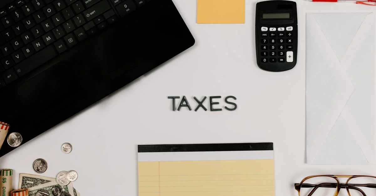 Fournitures de bureau organisées pour la gestion des impôts, comprenant une calculatrice, un clavier et un bloc-notes.