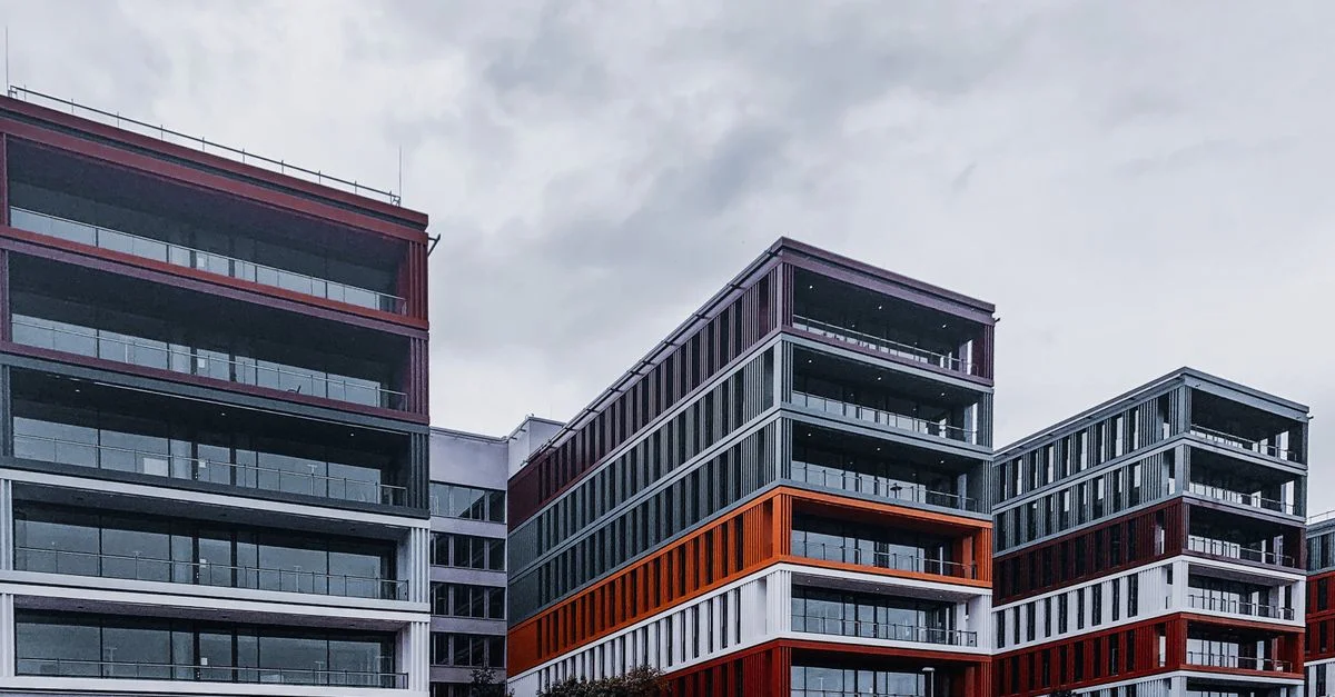 Bâtiments de bureaux contemporains avec des accents rouges et orange dans un cadre urbain.