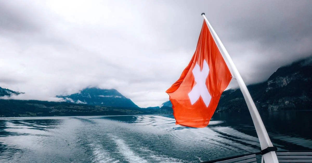 Une promenade en bateau sereine avec un drapeau suisse flottant, entourée de vues imprenables sur les montagnes.
