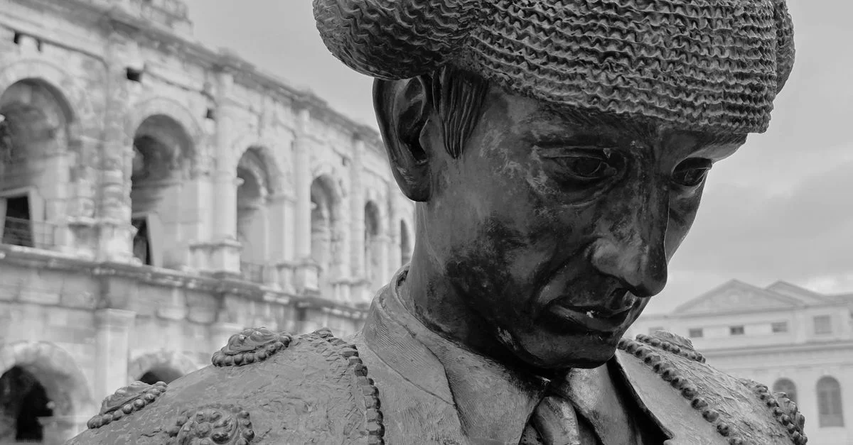 Statue en noir et blanc d'un matador près de l'ancien amphithéâtre de Nîmes, en France.