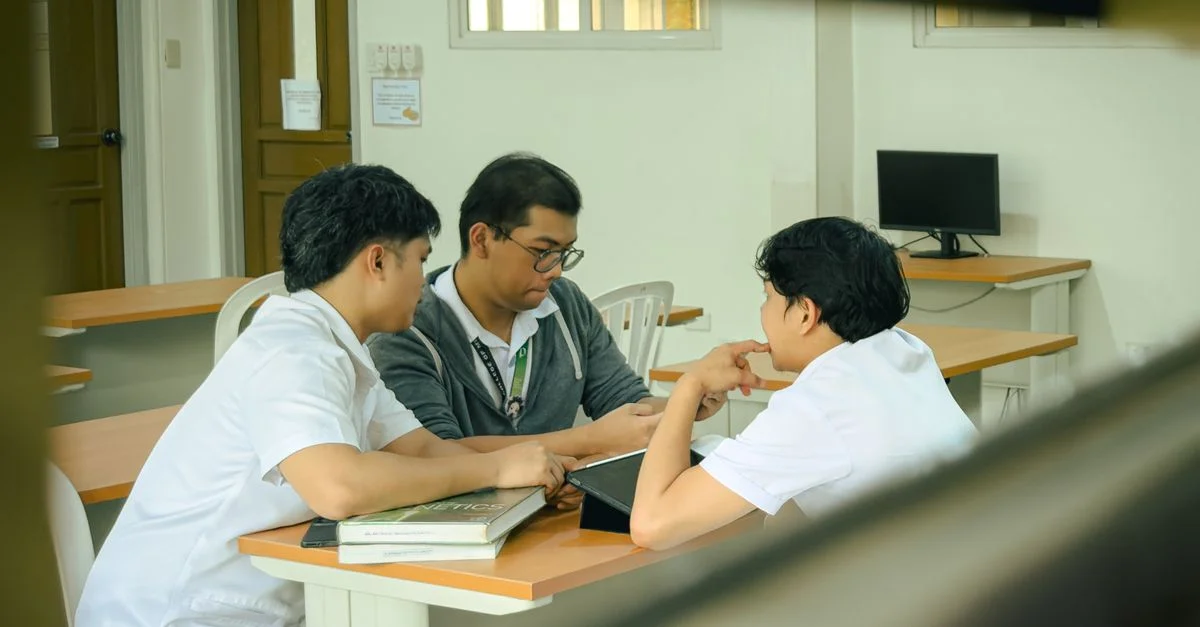 Trois étudiants collaborant sur un projet dans une salle de classe, favorisant le travail d'équipe et l'apprentissage.