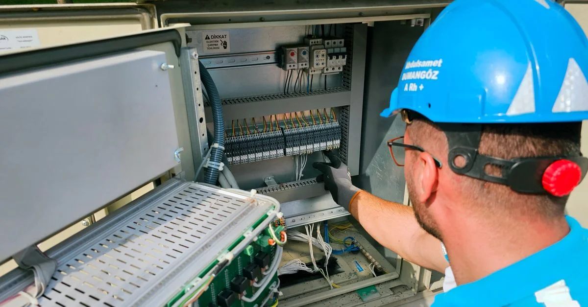 Un électricien travaille sur un tableau électrique extérieur, garantissant la sécurité et la fonctionnalité.