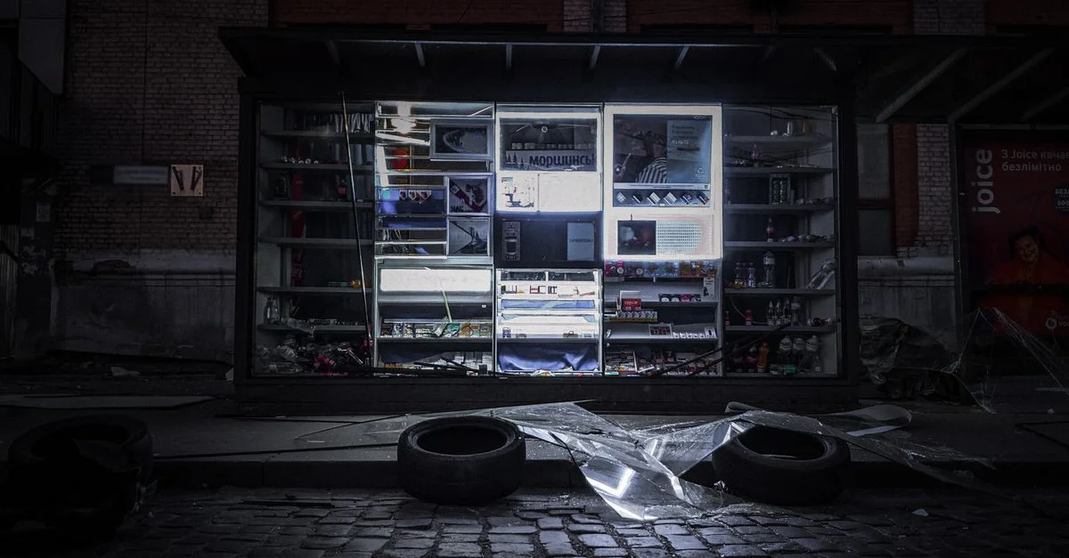 Une vitrine à Kyiv illuminée la nuit, mettant en valeur des produits au milieu des pavés.