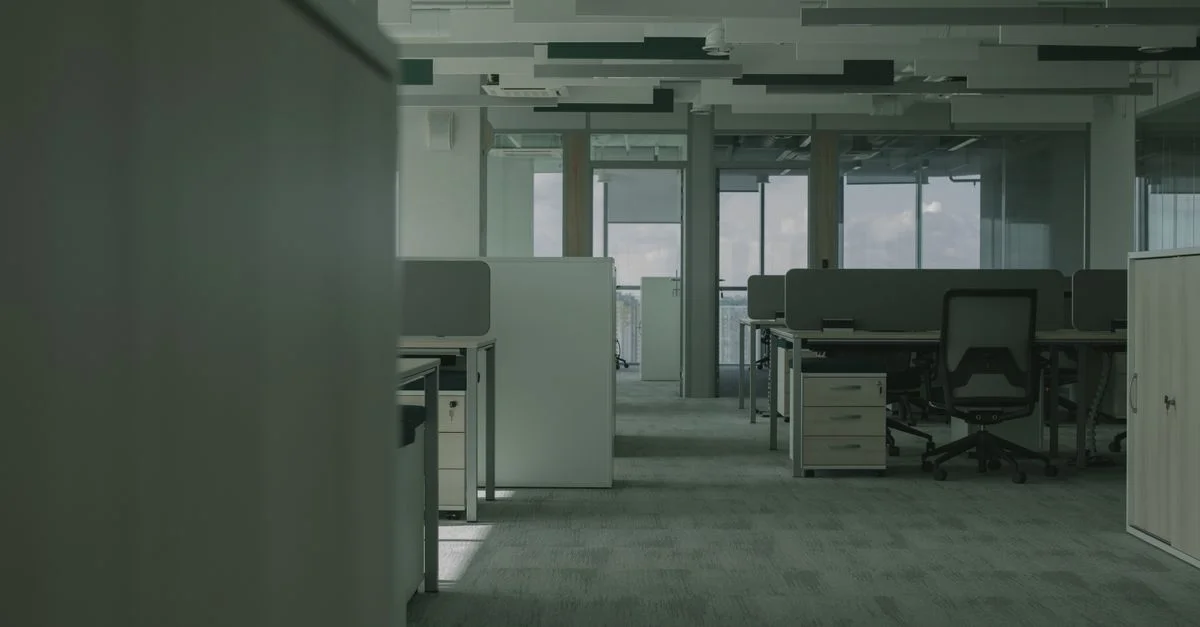Bureau spacieux et vide avec des bureaux modernes, des chaises et des cloisons.