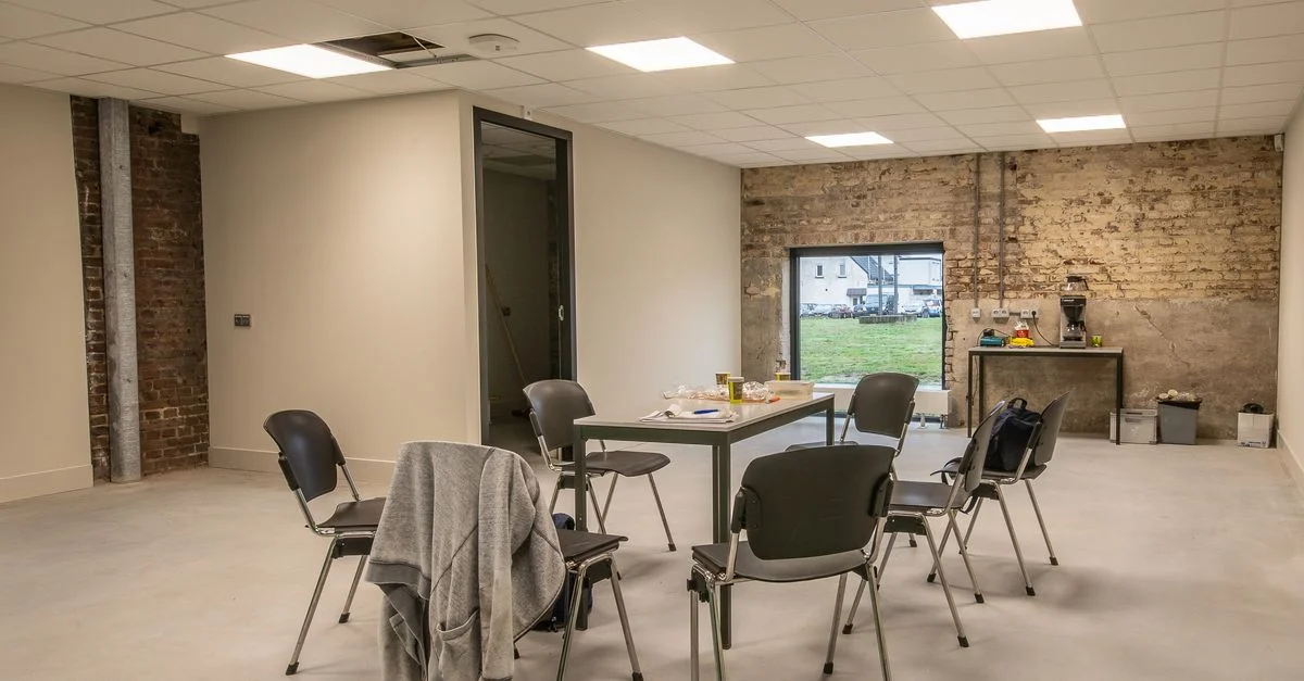 Salle de réunion lumineuse et minimaliste avec des chaises vides et une table dans un espace industriel moderne.