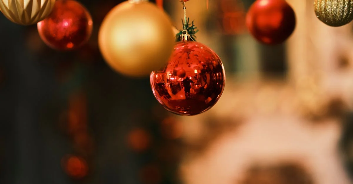 Gros plan sur des décorations de Noël rouges et dorées brillantes suspendues à l'intérieur, capturant l'esprit festif des fêtes.