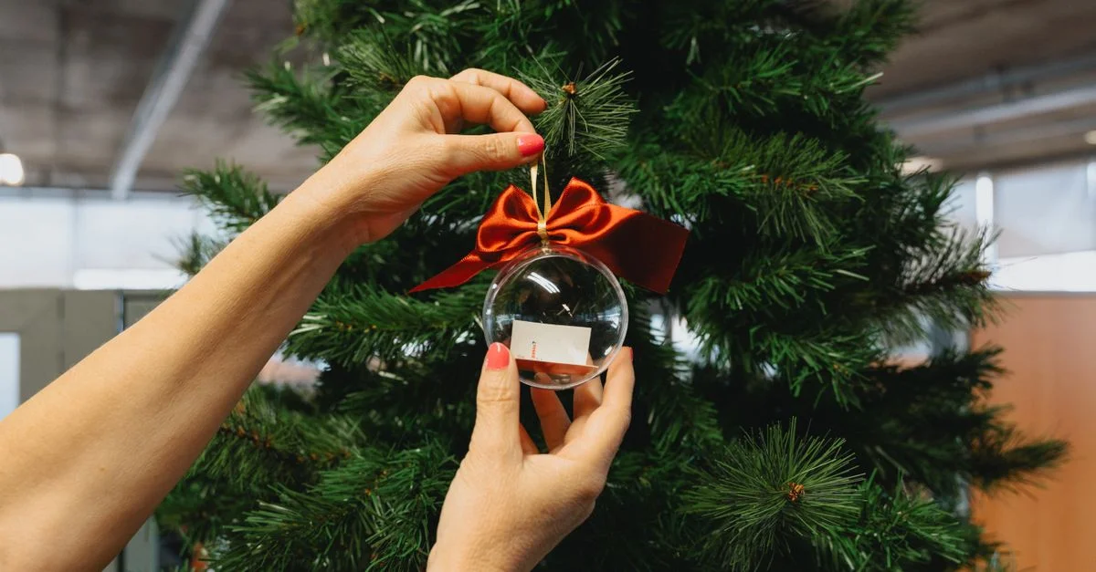 Une femme décore un sapin de Noël avec une boule en verre dans un cadre intérieur à Curitiba, au Brésil.