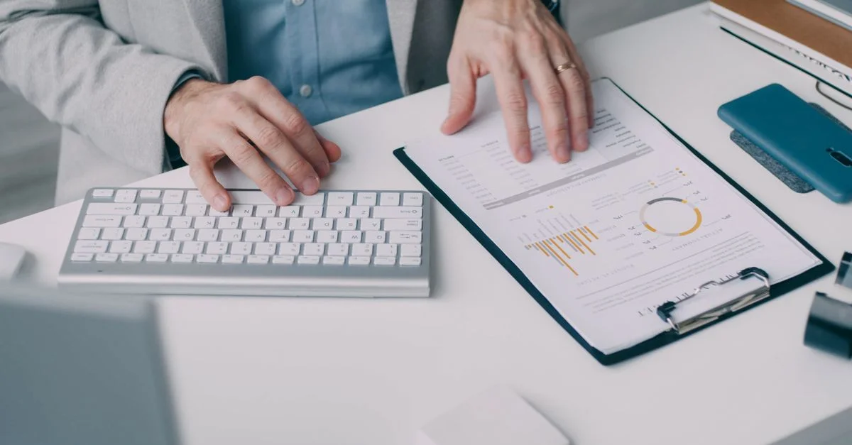 Un homme travaillant avec un rapport financier et un clavier dans un bureau.