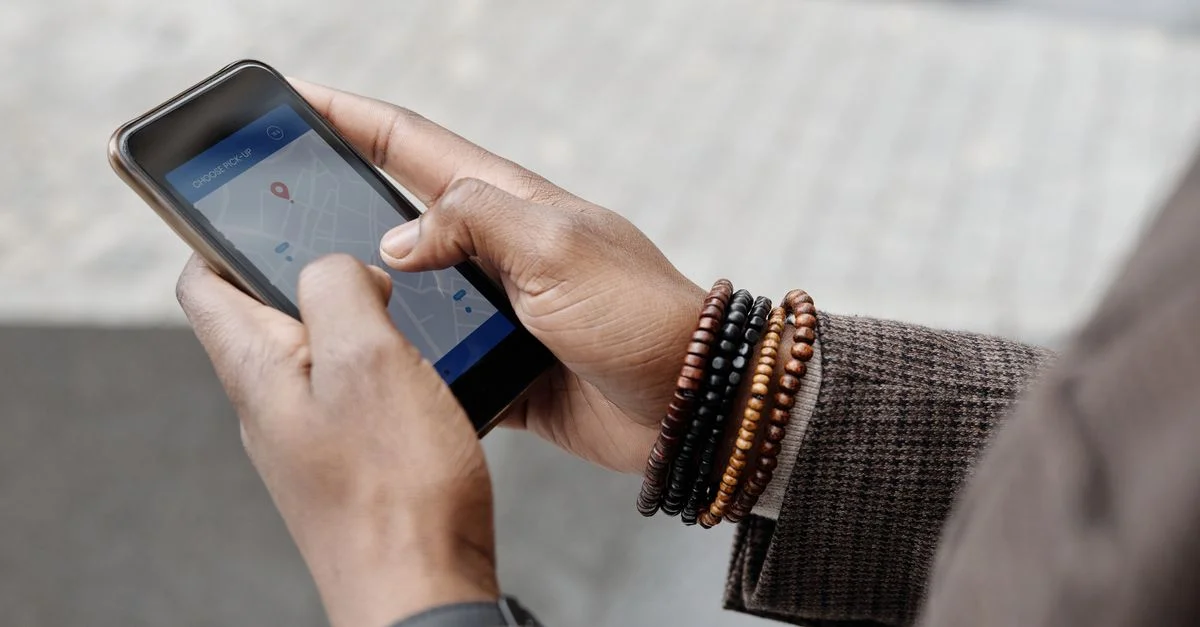 Gros plan sur des mains avec des bracelets utilisant une application GPS sur un smartphone à l'extérieur.