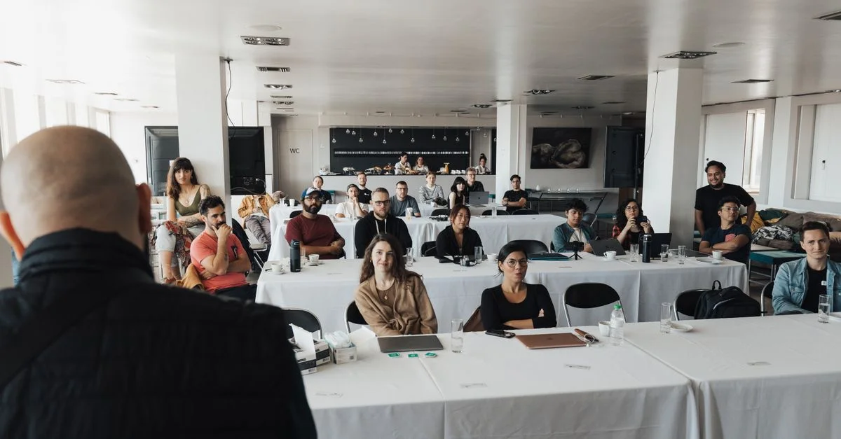Un groupe diversifié de professionnels du secteur des affaires assistent à une présentation dans une salle de conférence moderne.
