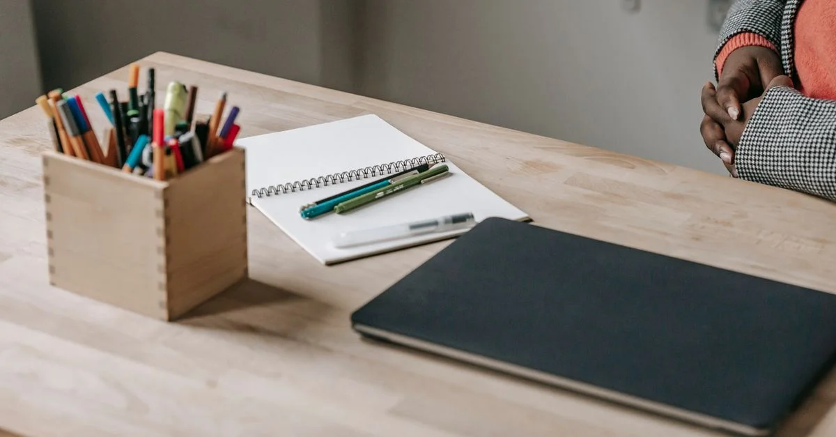 Un bureau bien rangé avec un ordinateur portable fermé, un carnet et des stylos dans un cadre de bureau moderne.