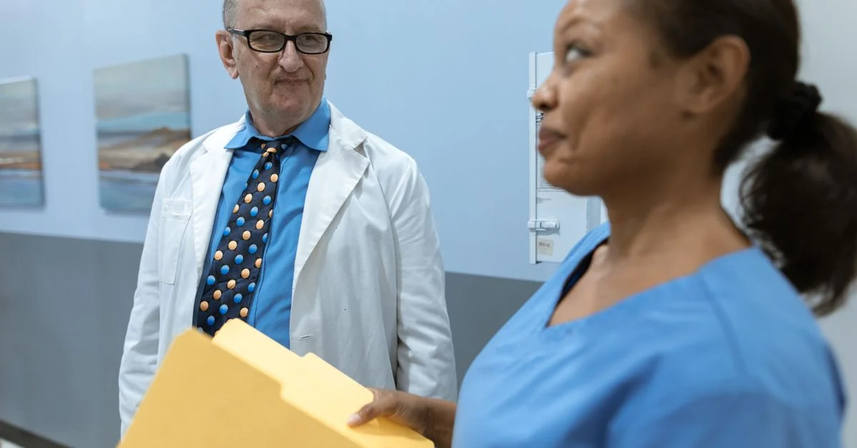 Un médecin et une infirmière discutent des dossiers des patients dans un couloir d'hôpital.