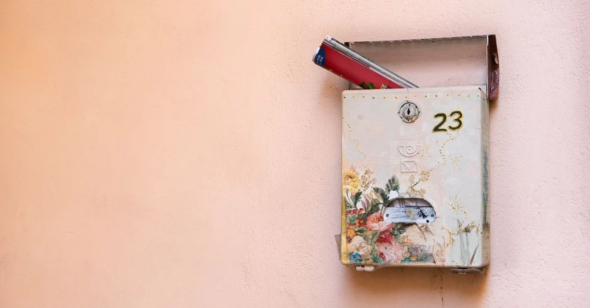 Une boîte aux lettres décorative sur un mur contenant des magazines, marquée du numéro 23.