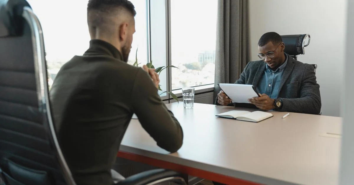 Un entretien d'embauche se déroulant dans un bureau moderne entre deux hommes professionnels.