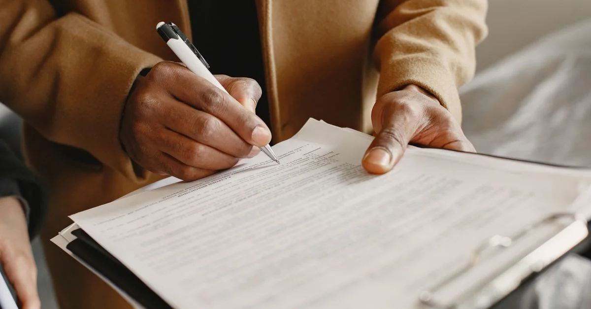 Gros plan d'une personne signant un contrat sur un clip, axé sur les formalités légales.