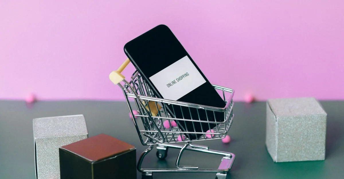 Un smartphone avec un chariot de shopping illustrant le concept de shopping en ligne dans un studio coloré.