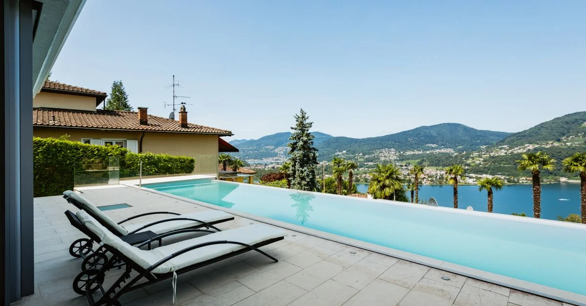 Élégante piscine à débordement au bord du lac offrant une vue imprenable sur les montagnes et l'eau, idéale pour la détente et les loisirs d'été.
