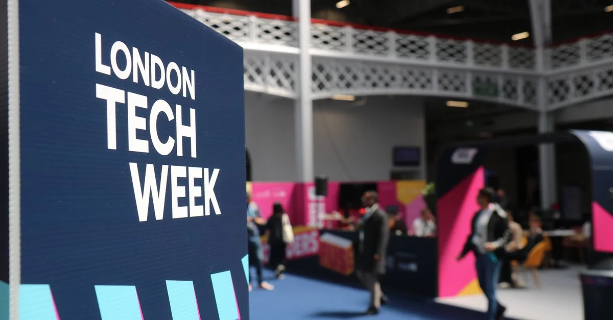 Ambiance intérieure animée à la London Tech Week, avec des participants et des stands colorés.