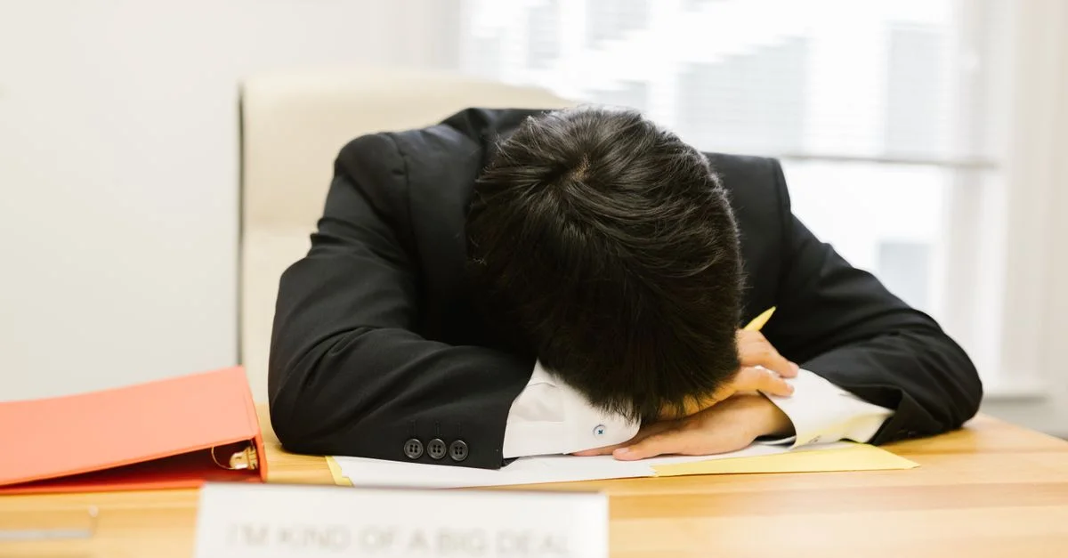 Personne d'affaires endormie sur un bureau dans un bureau, illustrant la fatigue au travail.