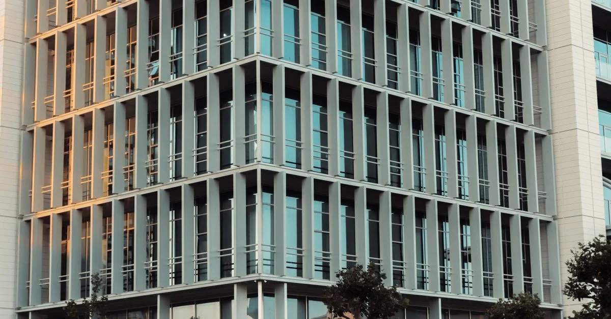 Immeuble de bureaux de grande hauteur avec fenêtres en verre réfléchissant et design moderne.