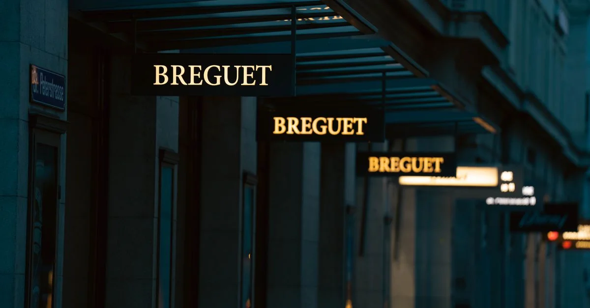 Une exposition d'enseignes Breguet dans une rue de la ville au crépuscule, mettant en valeur l'ambiance d'un magasin de luxe.